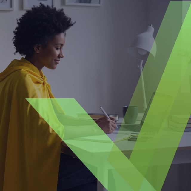 Person writing at desk with laptop and books, green checkmark overlay.